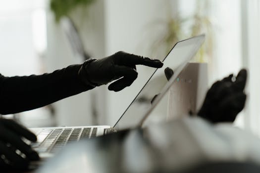pexels-photo-4123759-4123759 Close-up of a gloved hand interacting with a laptop in a sleek, modern office environment.
